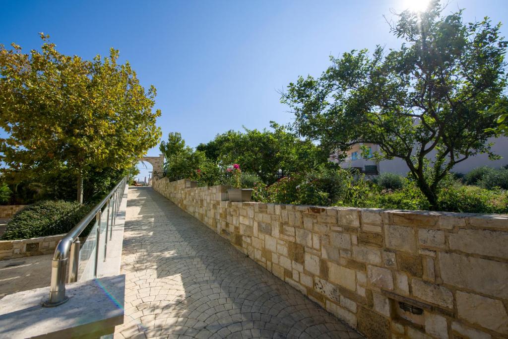 a stone retaining wall next to a sidewalk at Isida Hotel Agia Marina in Agia Marina Nea Kydonias