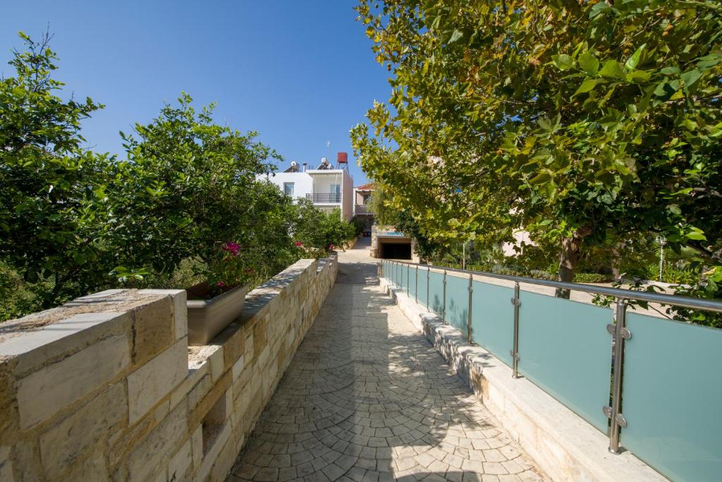 a walkway next to a retaining wall next to a swimming pool at Isida Hotel Agia Marina in Agia Marina Nea Kydonias