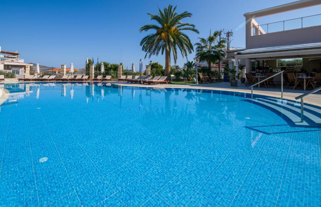a large blue swimming pool next to a building at Isida Hotel Agia Marina in Agia Marina Nea Kydonias