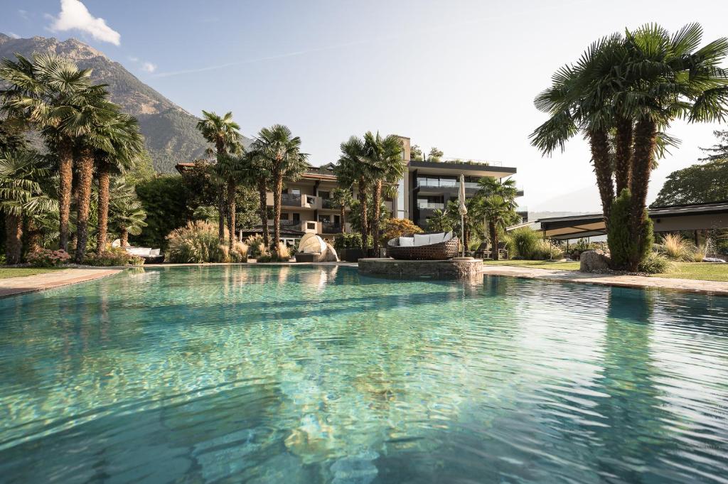 una gran piscina con palmeras y un edificio en Hotel Das Dorner, en Lagundo