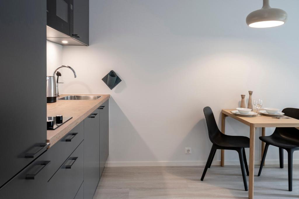 uma cozinha com uma mesa de madeira e cadeiras pretas em HOOM HOME & HOTEL Sigtuna em Rosersberg