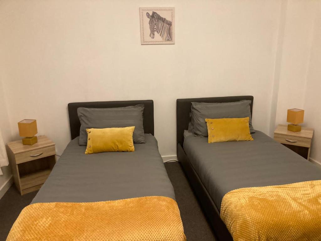 two beds with yellow pillows in a room at The Graye House in Sheffield