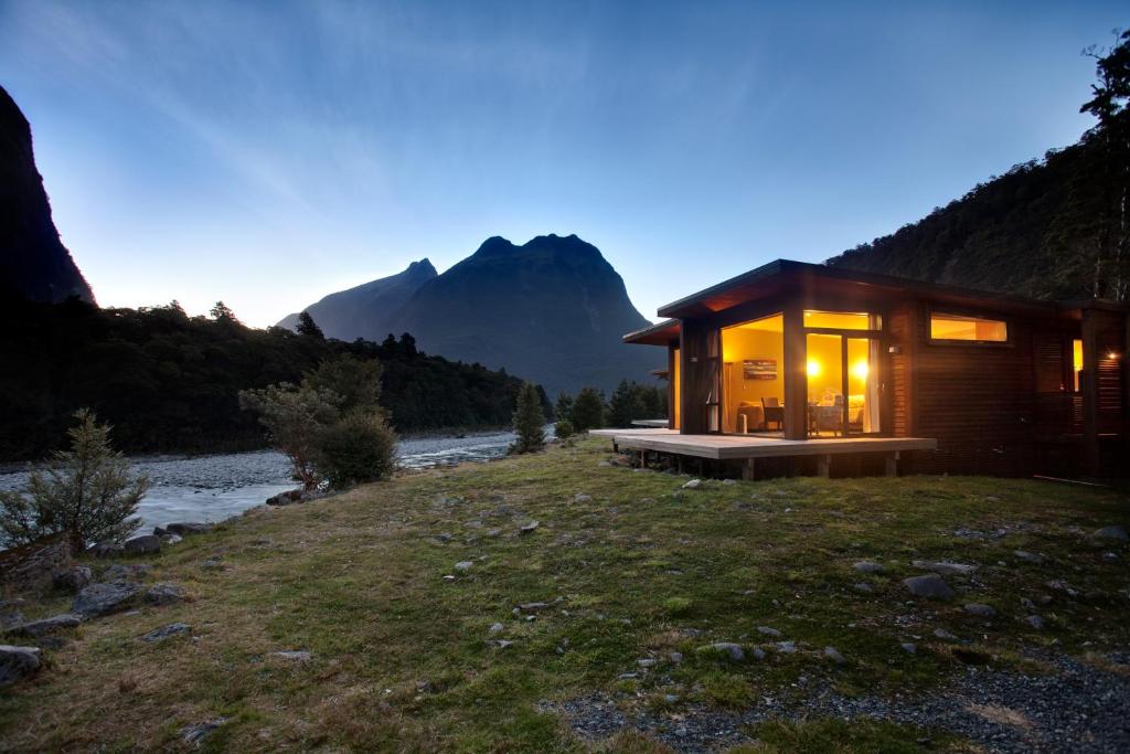 a wooden cabin on a hill next to a river at Milford Sound Lodge in Milford Sound
