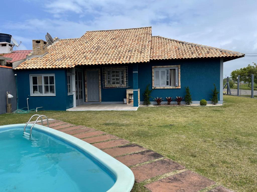 uma casa azul com uma piscina em frente em Casa Família Sander em Imbé