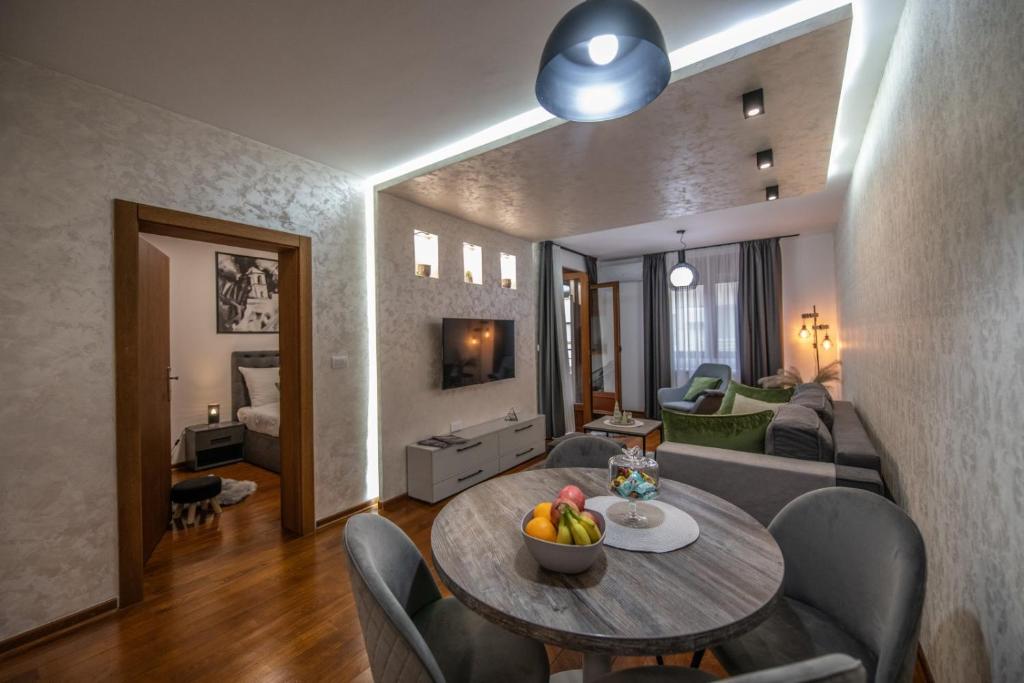 NOVAK 1 apartman في Vrnjačka Banja: غرفة معيشة مع طاولة وأريكة