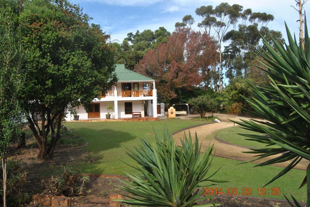 a white house with a green roof in a yard at Robin's Nest in Hermanus