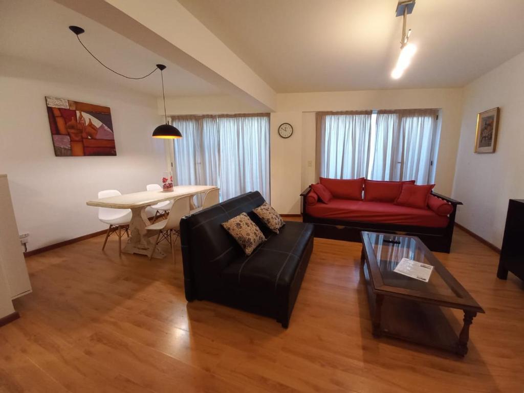 sala de estar con sofá rojo y mesa en Departamento Centro Cívico en San Carlos de Bariloche