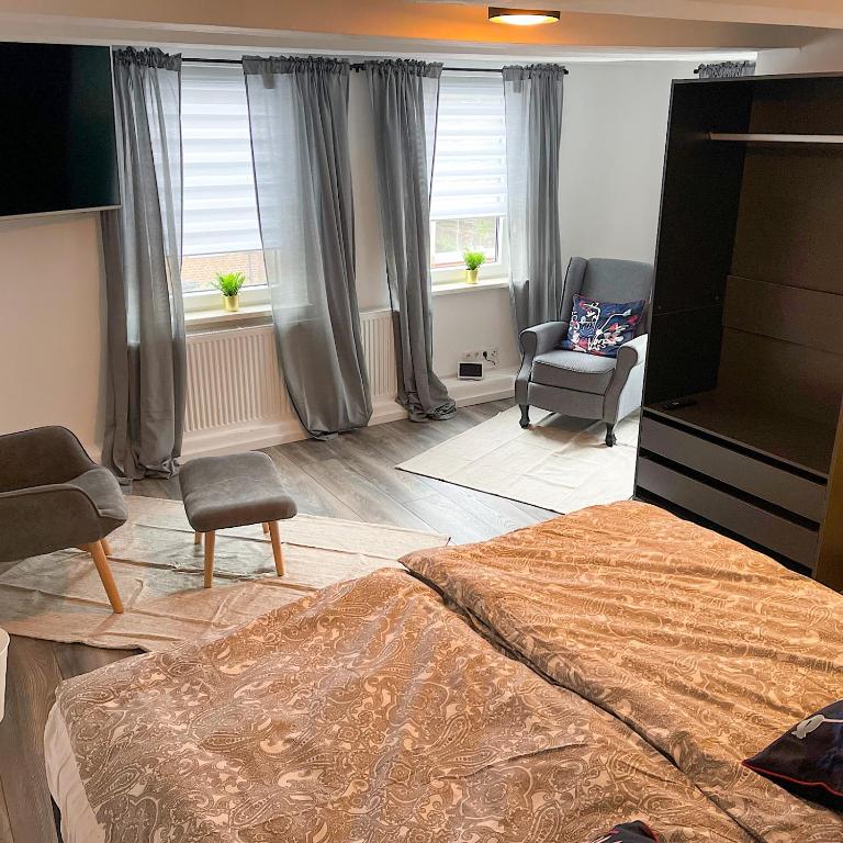 a bedroom with a bed and a chair and windows at Fernweh Harz in Seesen