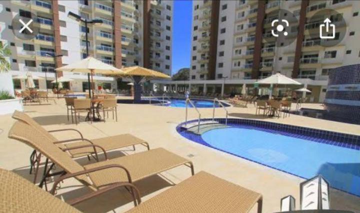 a swimming pool with tables and chairs next to a building at Apto confortável Grand Reserva Casa da Madeira! in Caldas Novas