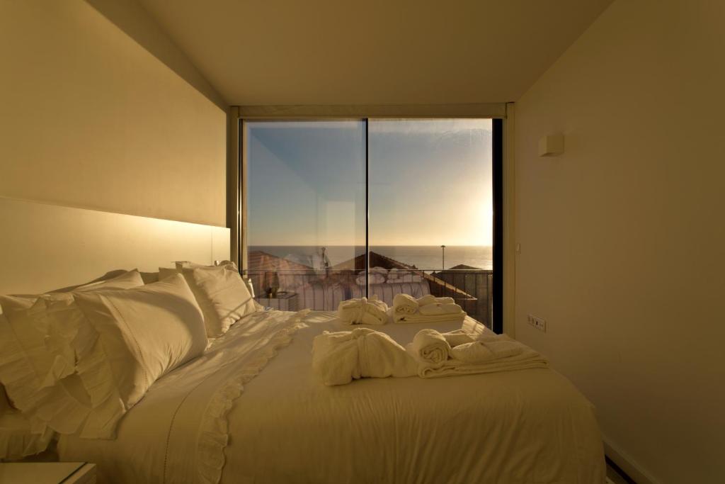 Boutique Rentals- Bliss By The Sea Apt- Ocean views in Foz Beach في بورتو: غرفة نوم بسرير أبيض مع نافذة كبيرة