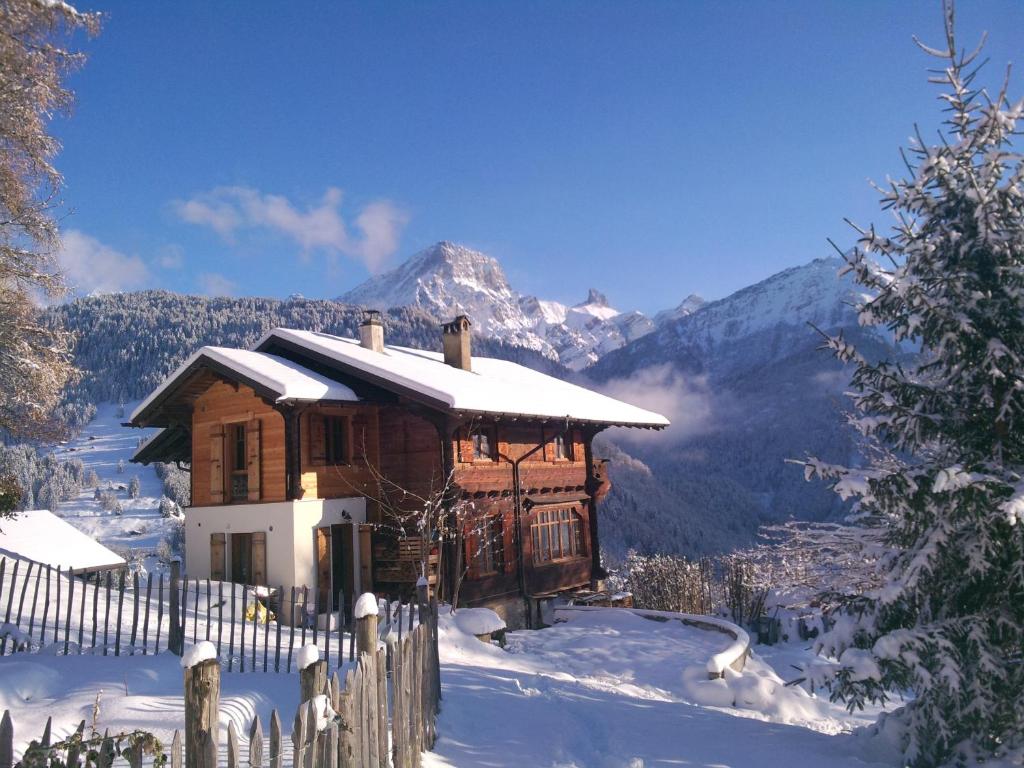 ein Holzhaus im Schnee mit einem Zaun in der Unterkunft Magnifique Chalet Valérie 5 chambres à coucher & vue unique in Gryon
