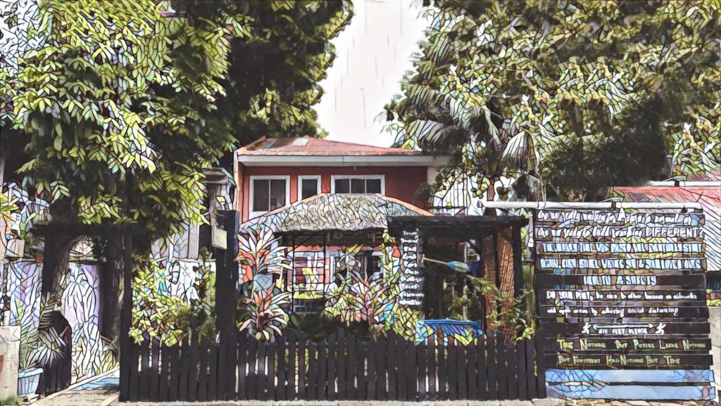 Una valla negra con una casa detrás. en Casa Isabel Hostel en Bantayan Island