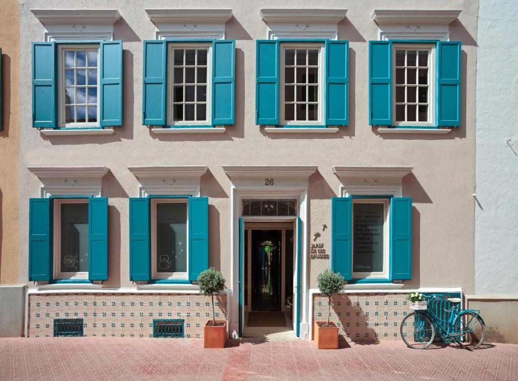 een gebouw met blauwe luiken en een fiets geparkeerd aan de voorkant bij Jardí de Ses Bruixes Boutique Hotel in Mahón