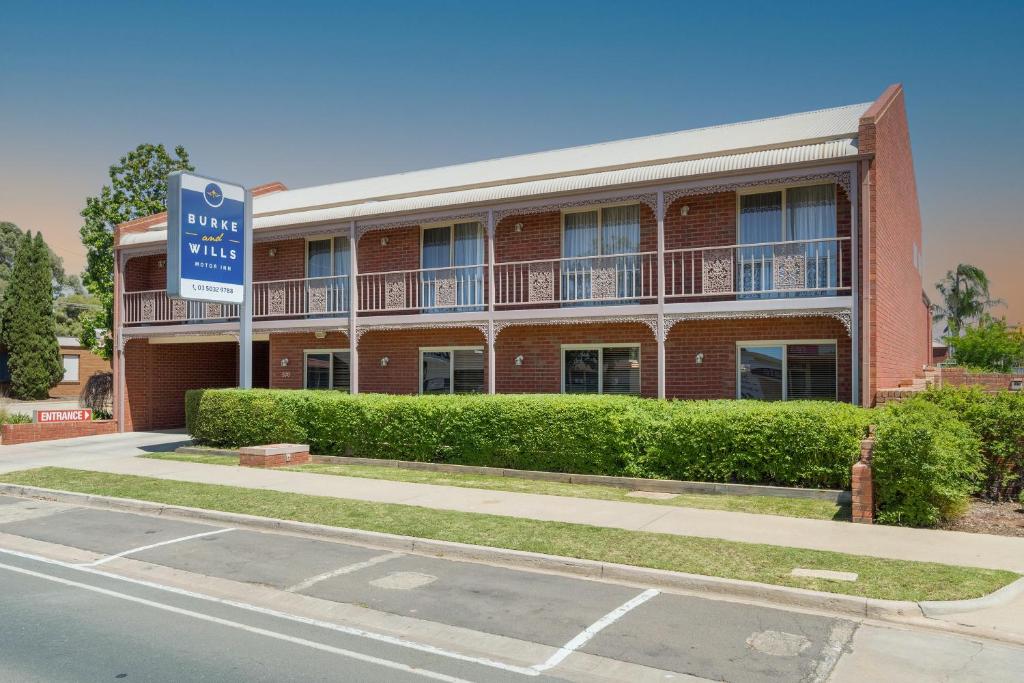 a red brick building with a blue sign in front of it at Burke And Wills Motor Inn Swan Hill in Swan Hill