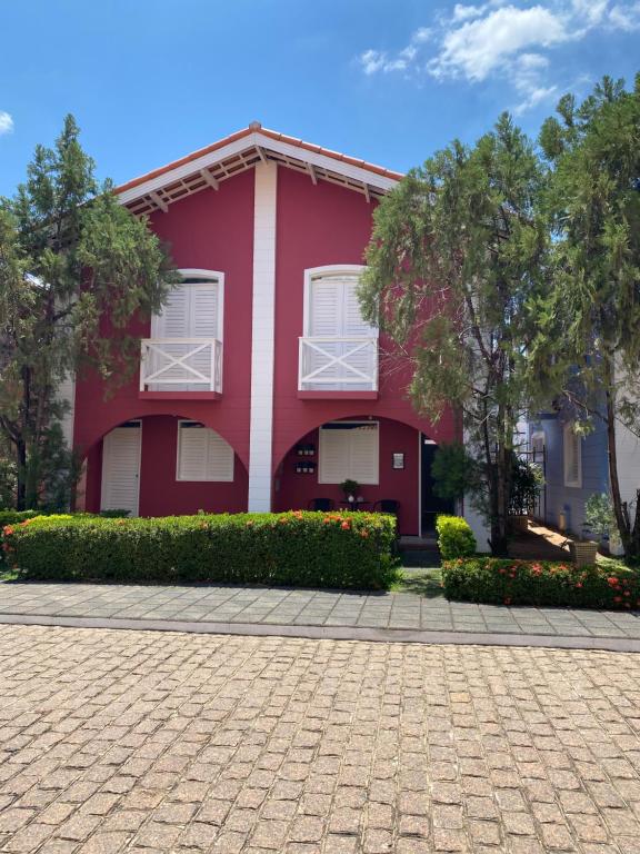 ein rotes Haus mit weißen Fenstern und einer steinernen Einfahrt in der Unterkunft Casa condomínio 2 suítes in Juazeiro do Norte