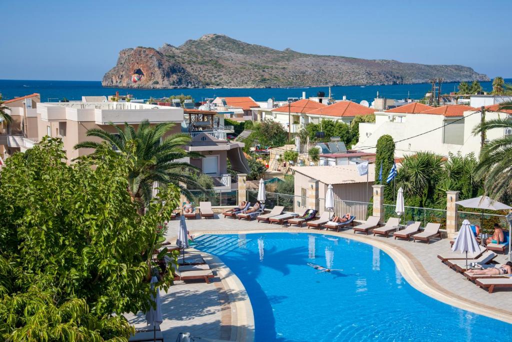 a view of the pool at a resort with chairs and the ocean at Isida Hotel Agia Marina in Agia Marina Nea Kydonias