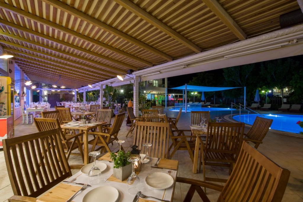a restaurant with tables and chairs and a pool at Isida Hotel Agia Marina in Agia Marina Nea Kydonias
