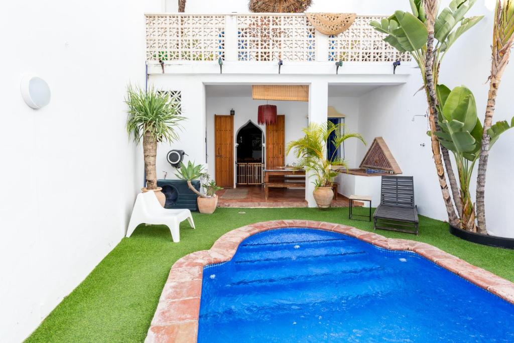 una piscina en medio de una casa con césped verde en El Patio Andaluz, en Vélez-Málaga