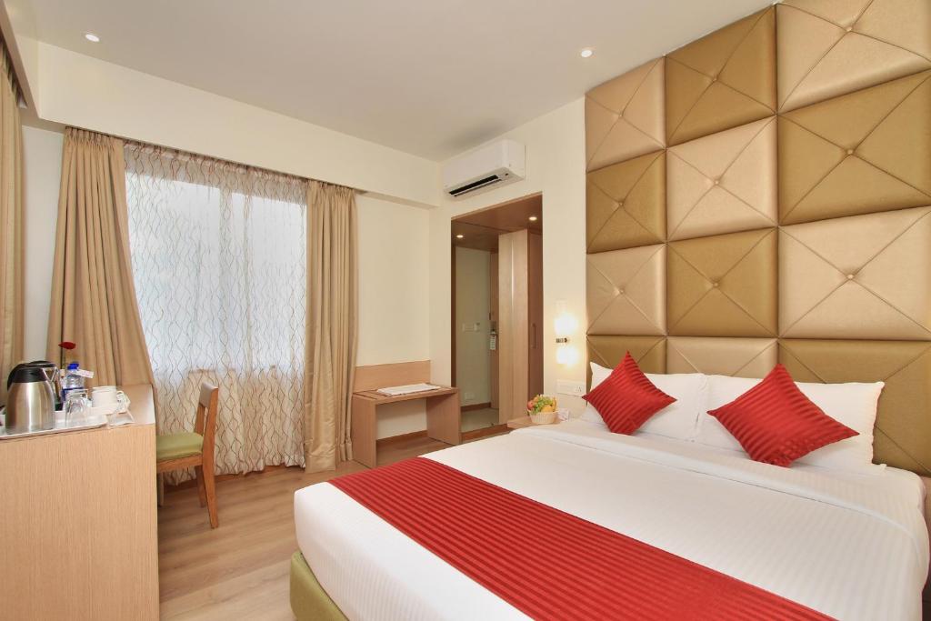 1 dormitorio con 1 cama grande con almohadas rojas en La Sara Regent, en Bangalore