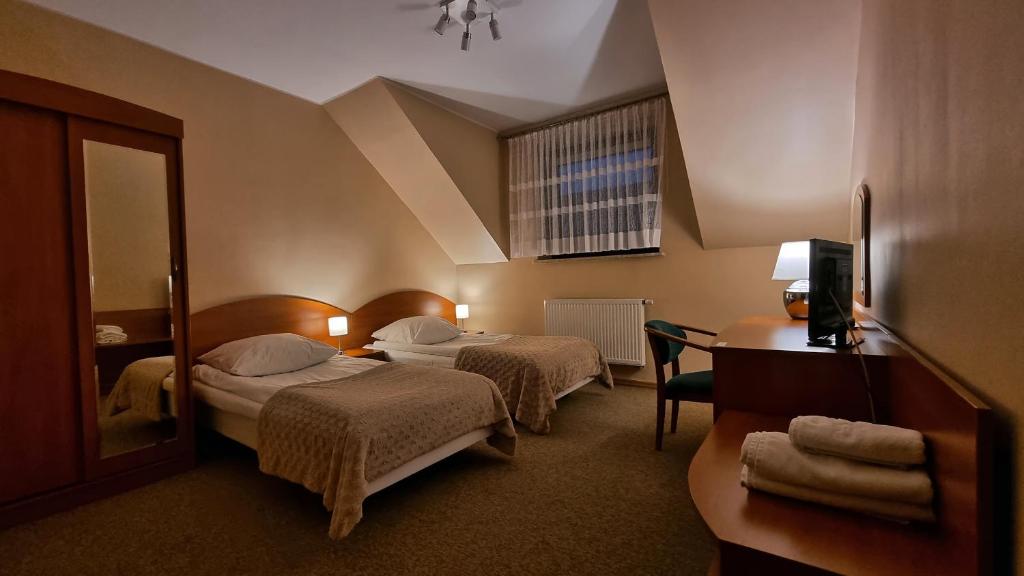 a hotel room with two beds and a mirror at Hotel Jola in Września