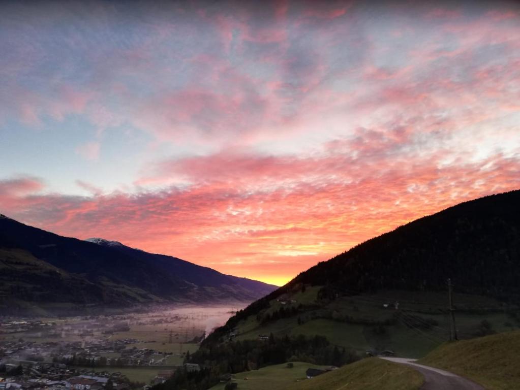 um pôr-do-sol sobre um vale com um rio e montanhas em Aignerbauer Mittersill em Mittersill