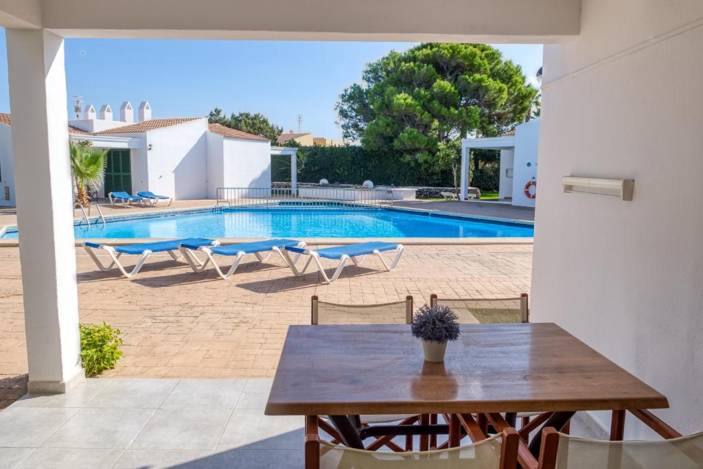 a patio with a table and a swimming pool at Apartamentos Las Golondrinas in Cala en Bosc