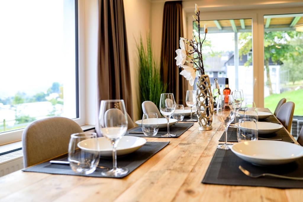 una larga mesa de madera con sillas y copas de vino en Smart Resorts Haus Opal Ferienwohnung 401, en Winterberg