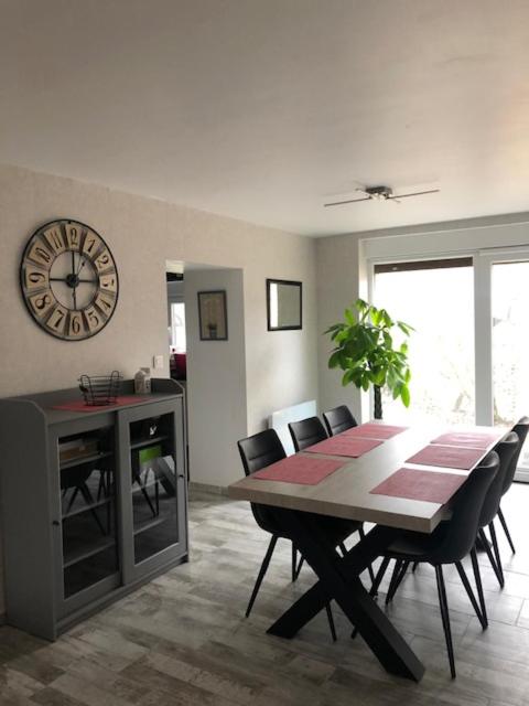 une salle à manger avec une table, des chaises et une horloge dans l'établissement Les Aubennes, à Fromelennes