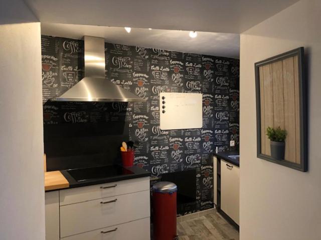 a kitchen with a black and white wall at Les Aubennes in Fromelennes