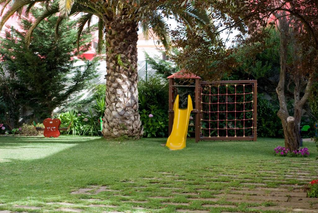 a playground with a yellow slide and a tree at Hotel Londres Estoril / Cascais in Estoril