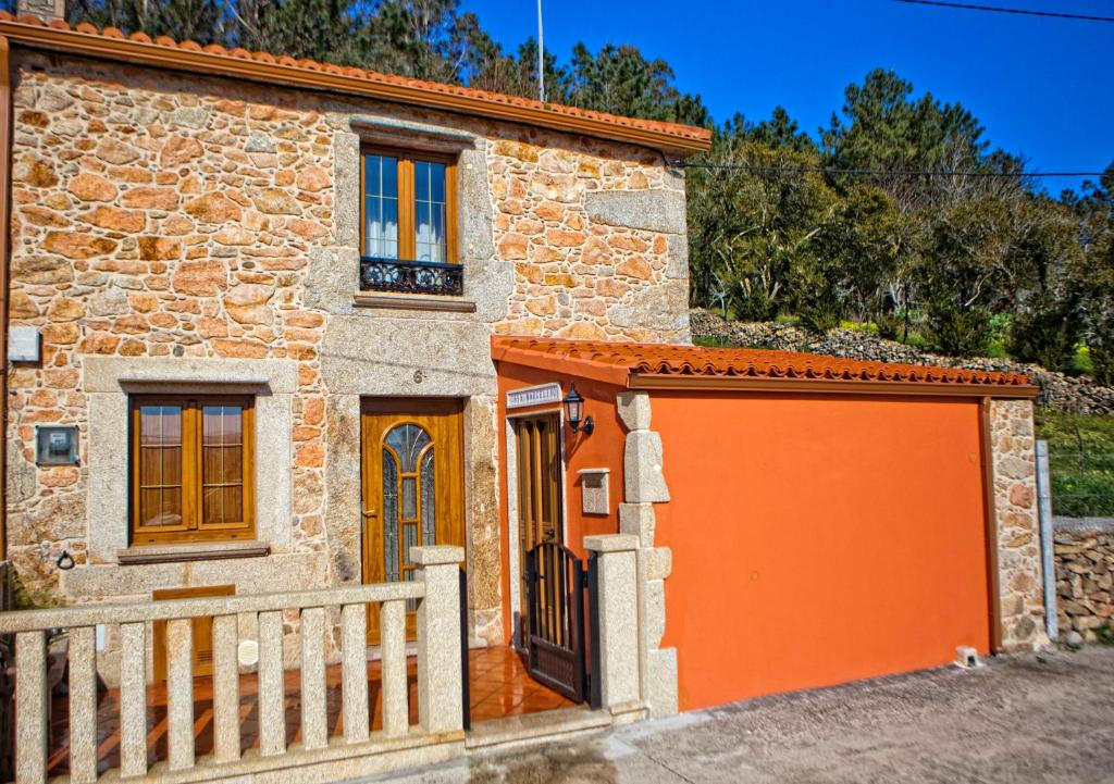 a stone house with an orange garage at Casa Marcelino in Muxia