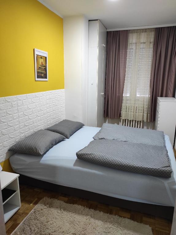 um quarto com uma cama e uma parede amarela em apartman Liman em Novi Sad