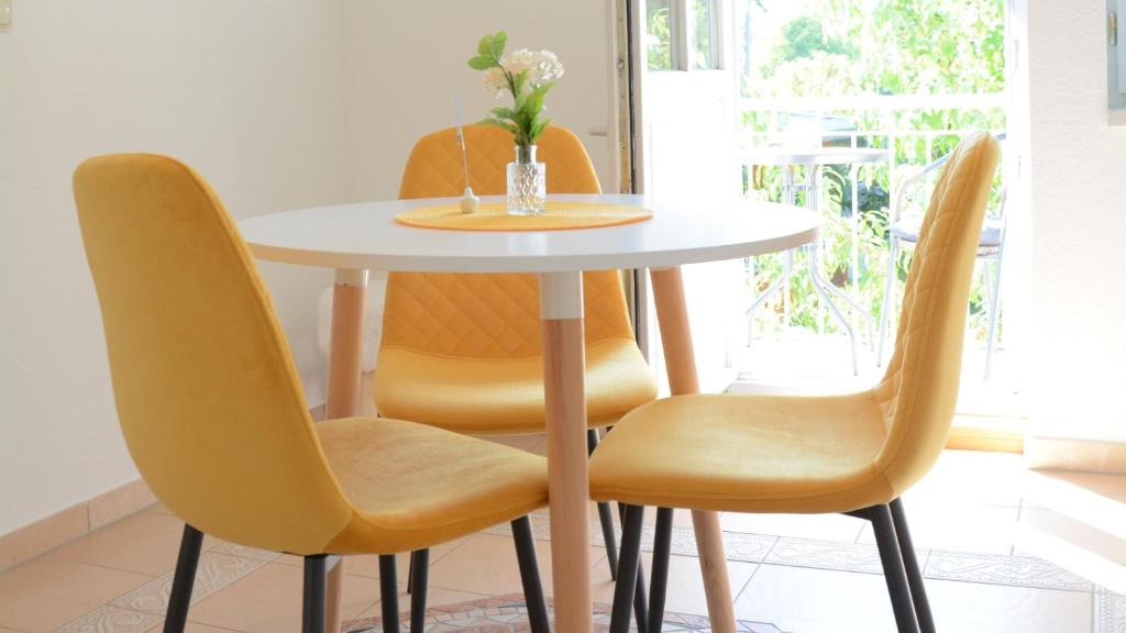 uma mesa branca com cadeiras amarelas e um vaso de flores em Rosenwinkel Appartement im OG em Halberstadt