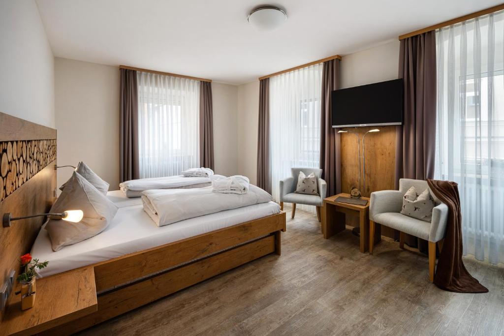 a bedroom with a large bed and two chairs at Hotel Zur Post in Bad Abbach