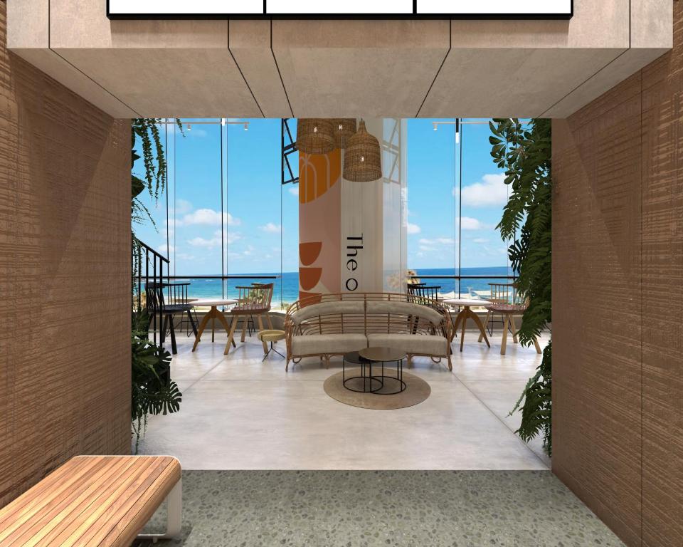 a lobby with chairs and tables and a view of the ocean at The O Pod Capsule Hotel in Tel Aviv