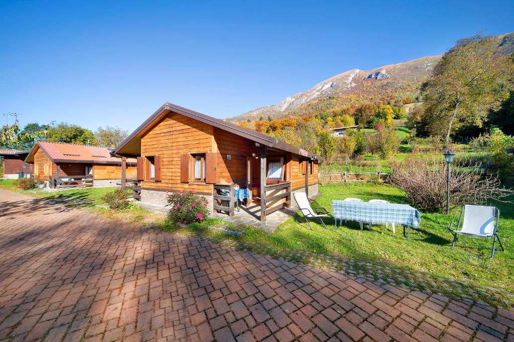 uma cabana de madeira com um banco e uma casa em Casa Rododendro em Barzio