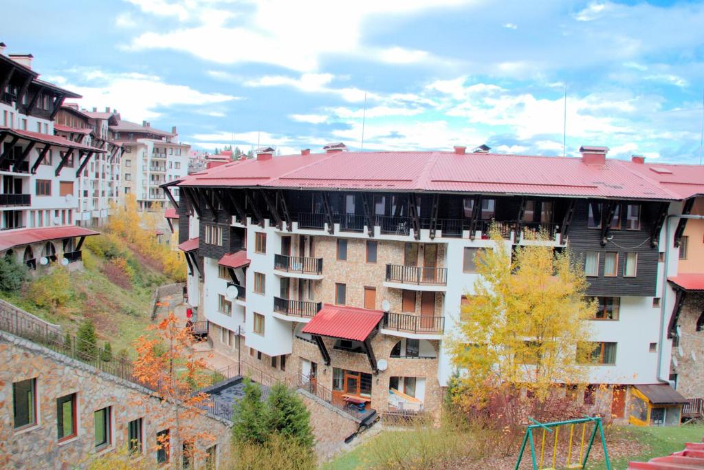 a building with a red roof in a city at Гранд Манастира Апартаменти "Зимна приказка" in Pamporovo