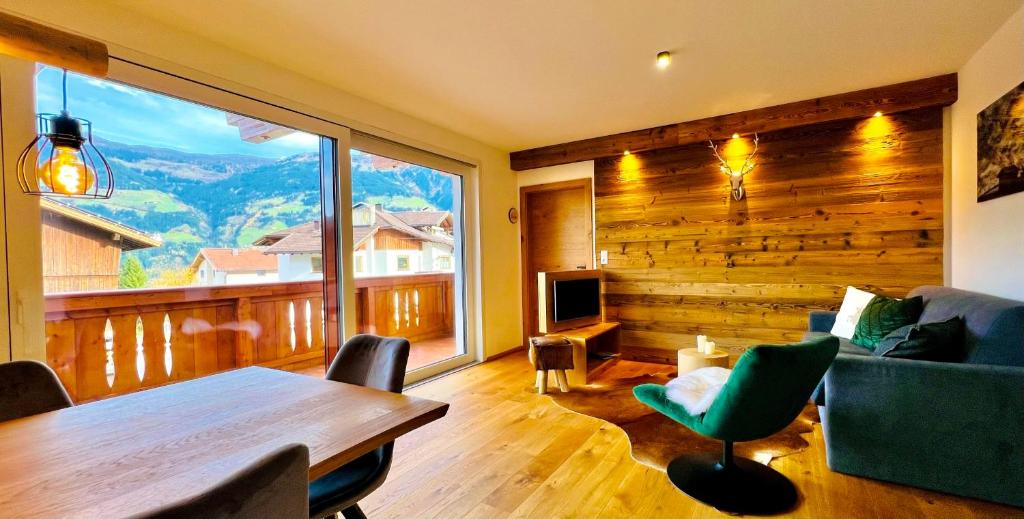 ein Wohnzimmer mit einem Tisch und einem großen Fenster in der Unterkunft Tiroler Zeitgeist Apartment Fügen in Fügen