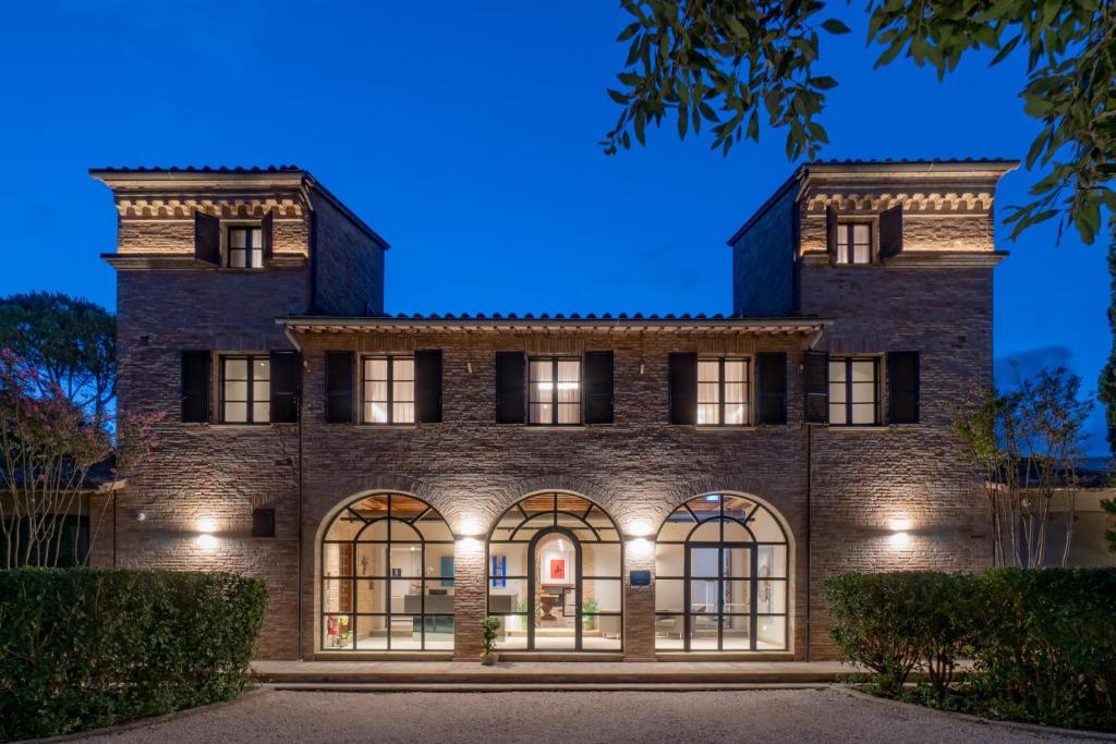 an exterior view of a large brick building at night at Le Cappuccinelle Suites&SPA in Perugia