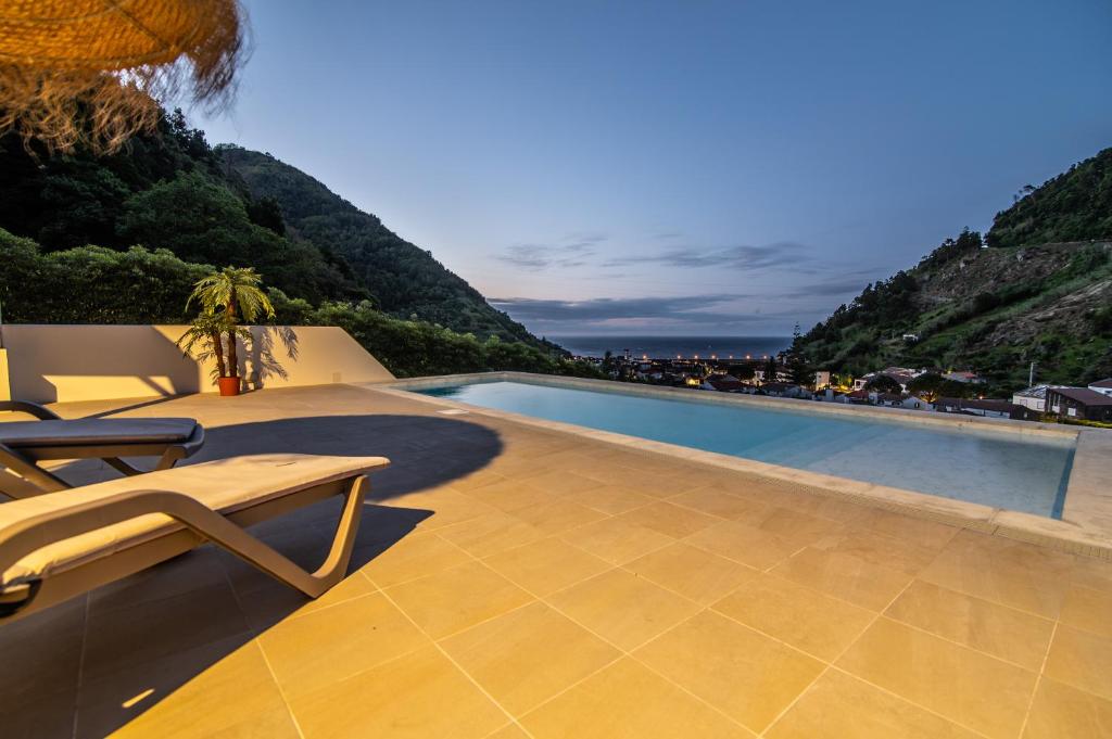 a swimming pool with a bench on a patio at Casa do Outeiro with Heated Pool 30C in Povoação