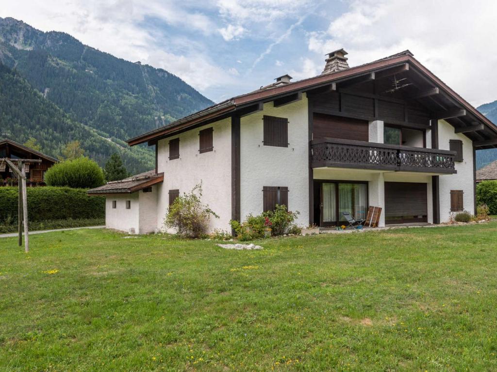 a white house with a balcony on a grass field at Appartement Chamonix-Mont-Blanc, 4 pièces, 6 personnes - FR-1-517-11 in Chamonix