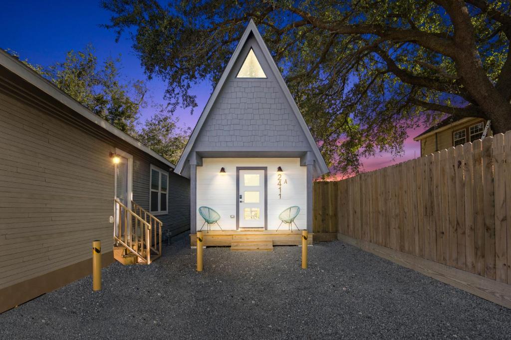 a small house with two chairs in front of a fence at Unique A-frame Tiny House in Houston Central in Houston