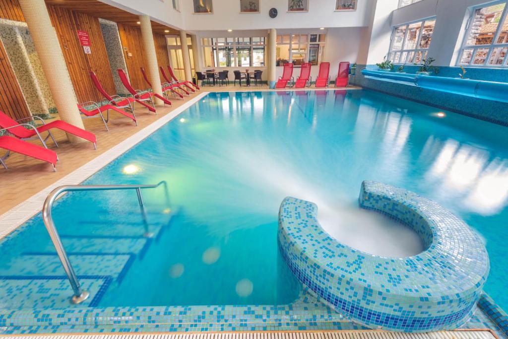 a large swimming pool with red chairs in a building at Lobogo Resort in Vlăhiţa