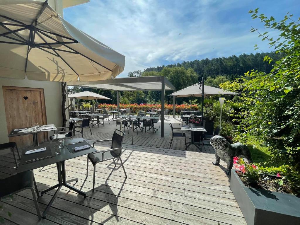 una terraza de madera con mesas, sillas y sombrillas en Hôtel Restaurant La Couronne by K en Reipertswiller