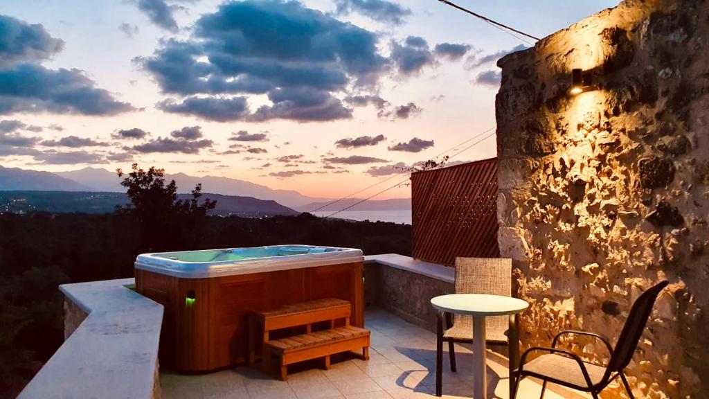 einen Whirlpool auf einer Terrasse mit einem Tisch und Stühlen in der Unterkunft Guesthouse Arkadi Spa in Atsipopoulo