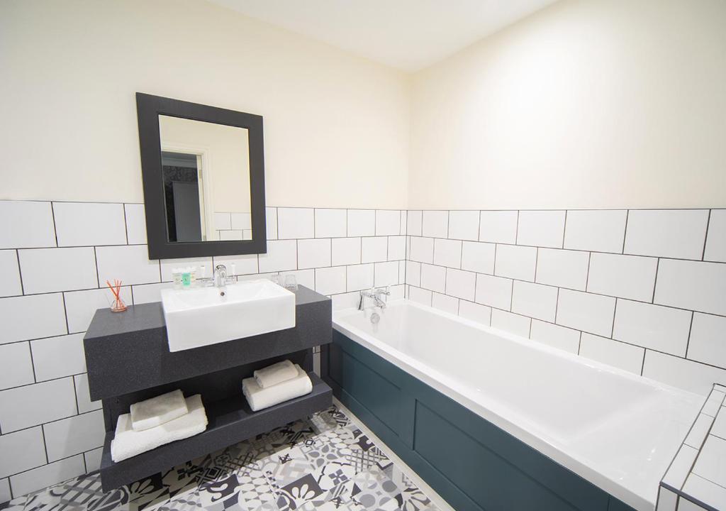 a bathroom with a sink and a tub and a mirror at Heacham Manor Hotel in Hunstanton