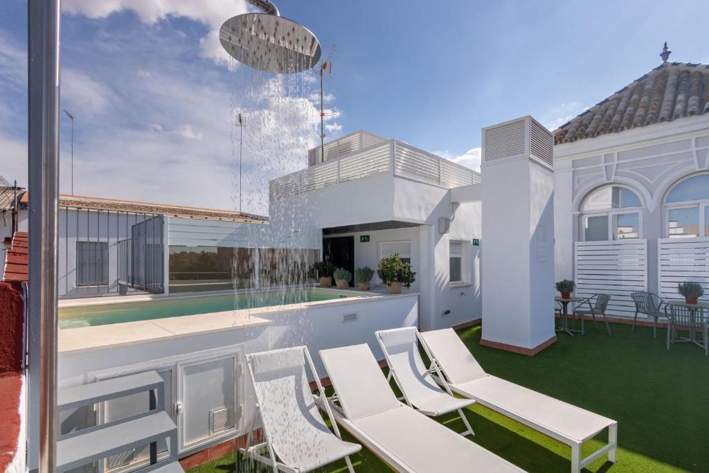 une terrasse avec des chaises blanches et une fontaine d'eau dans l'établissement LS9- La Palmera Luxury by Valcambre, à Séville