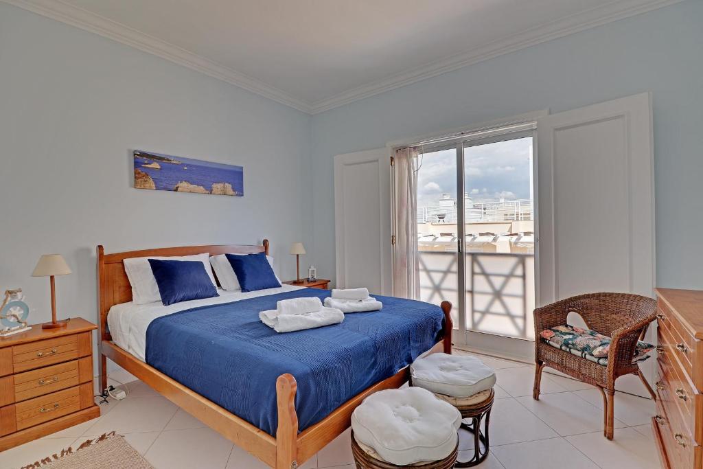 ヴィラモウラにあるVilamoura Main Avenue by Homingの青いシーツのベッドと窓のある寝室