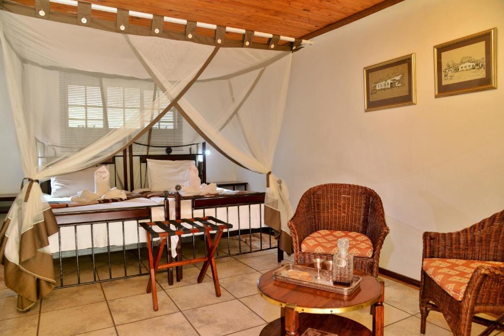 a room with chairs and a table and a bed at Kasane Self Catering in Kasane