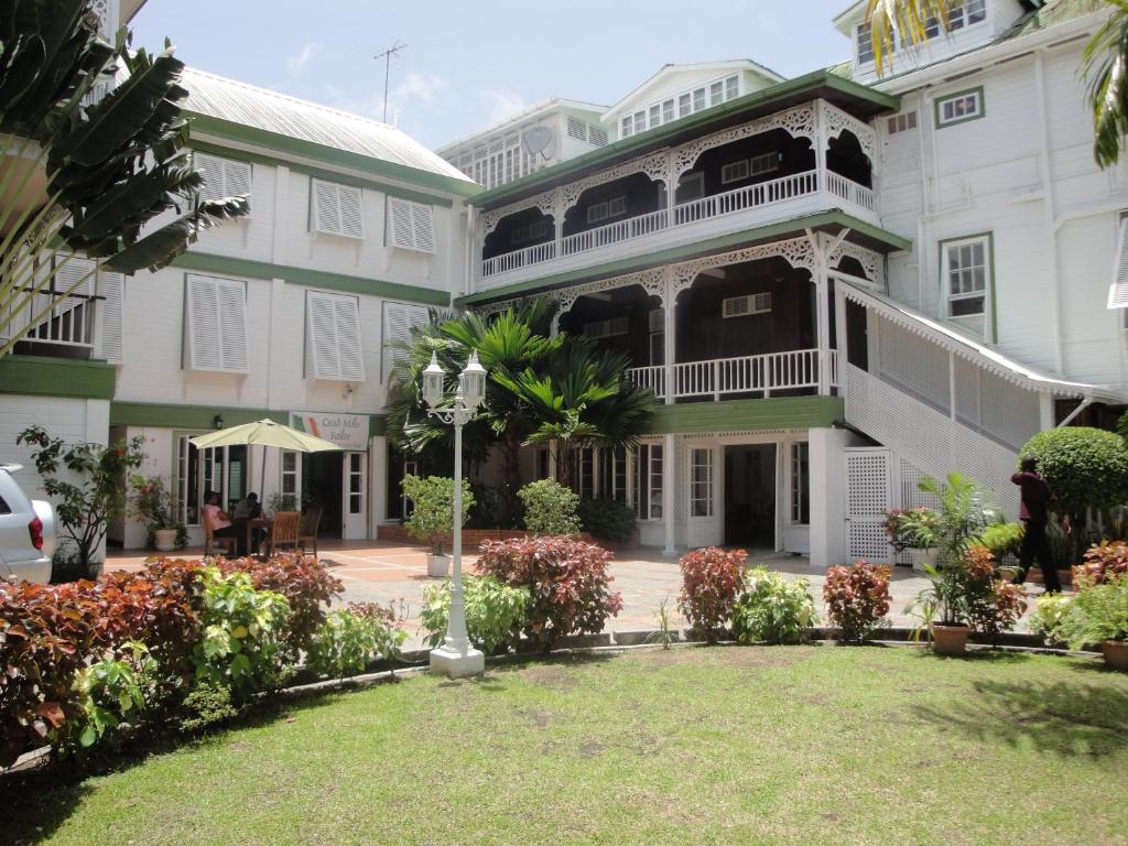 a large white building with a lawn in front of it at Cara Lodge Hotel in Georgetown
